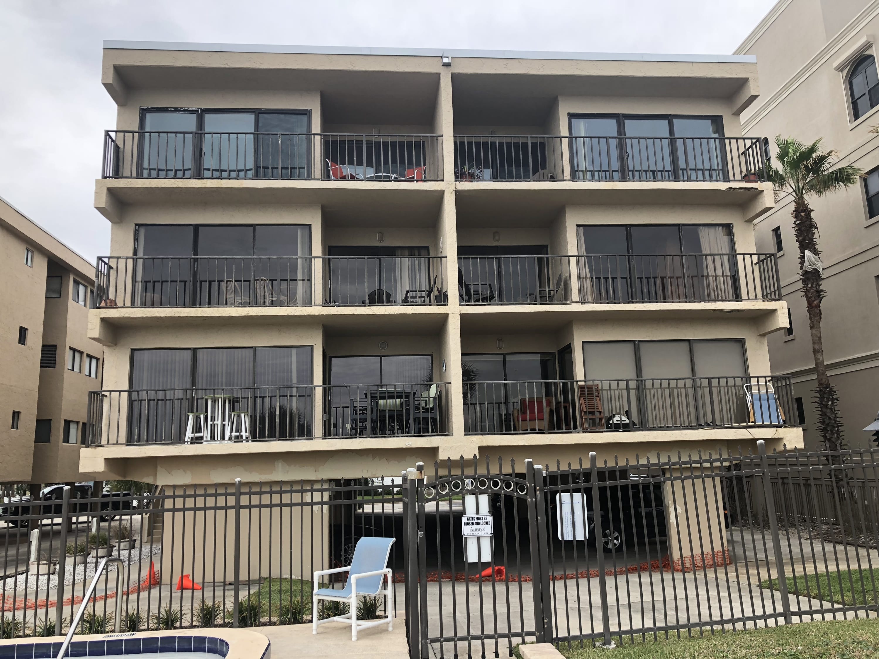 Multi-story coastal condominium building with tiered balconies and glass railings