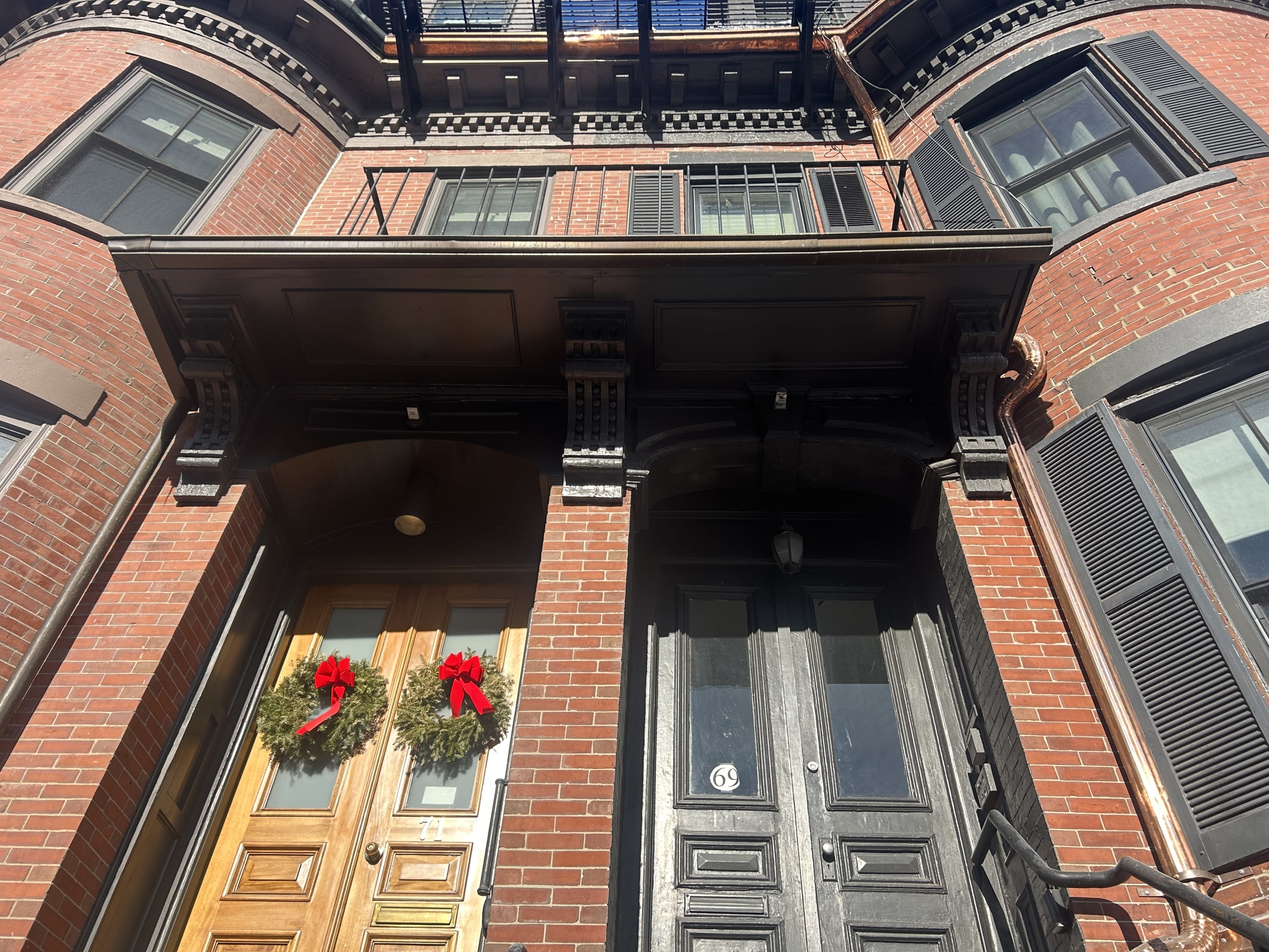 Historic townhouse entry canopy with decorative brackets and copper gutter in Boston