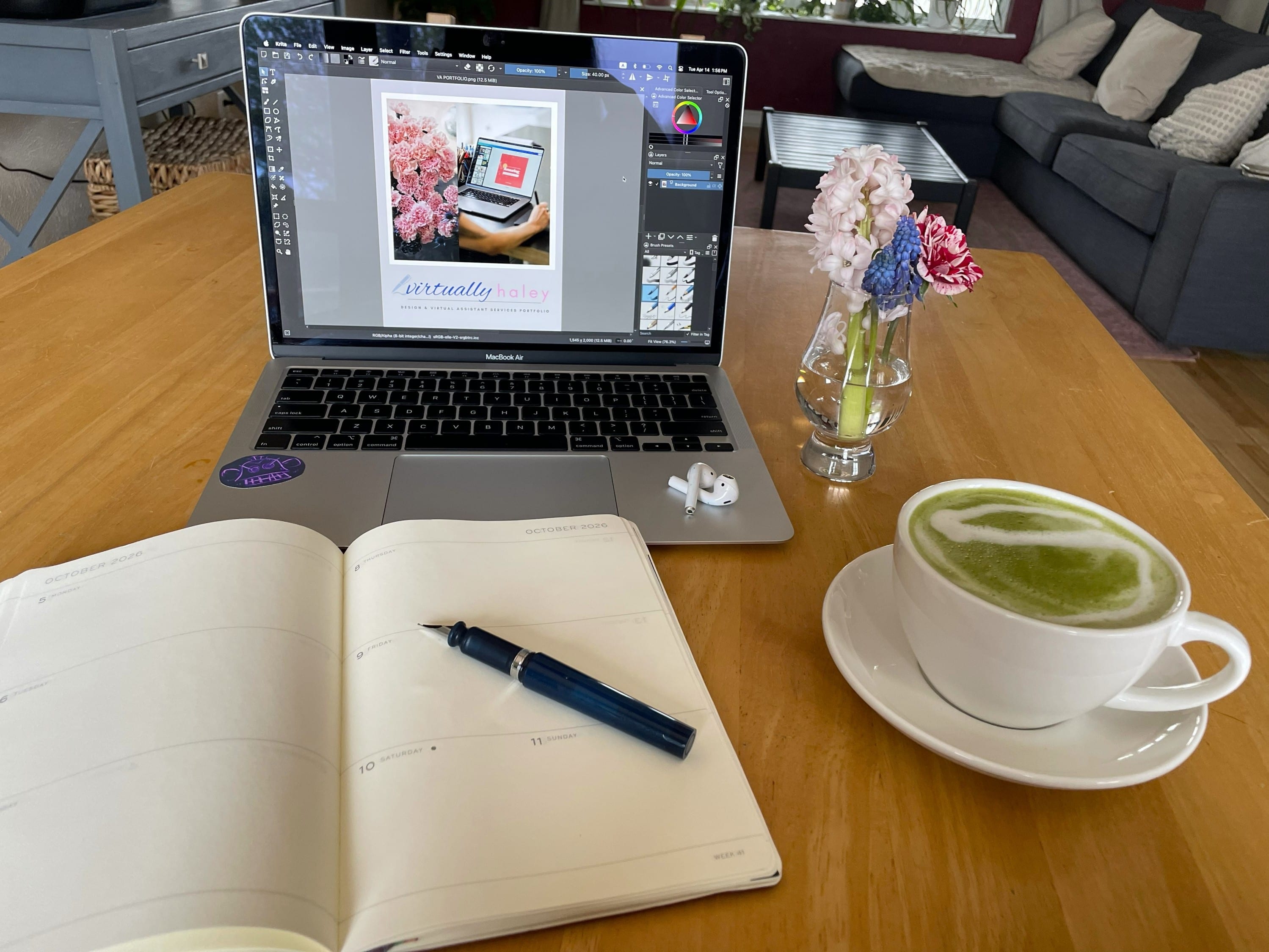 Laptop setup with planner, latte, and flowers