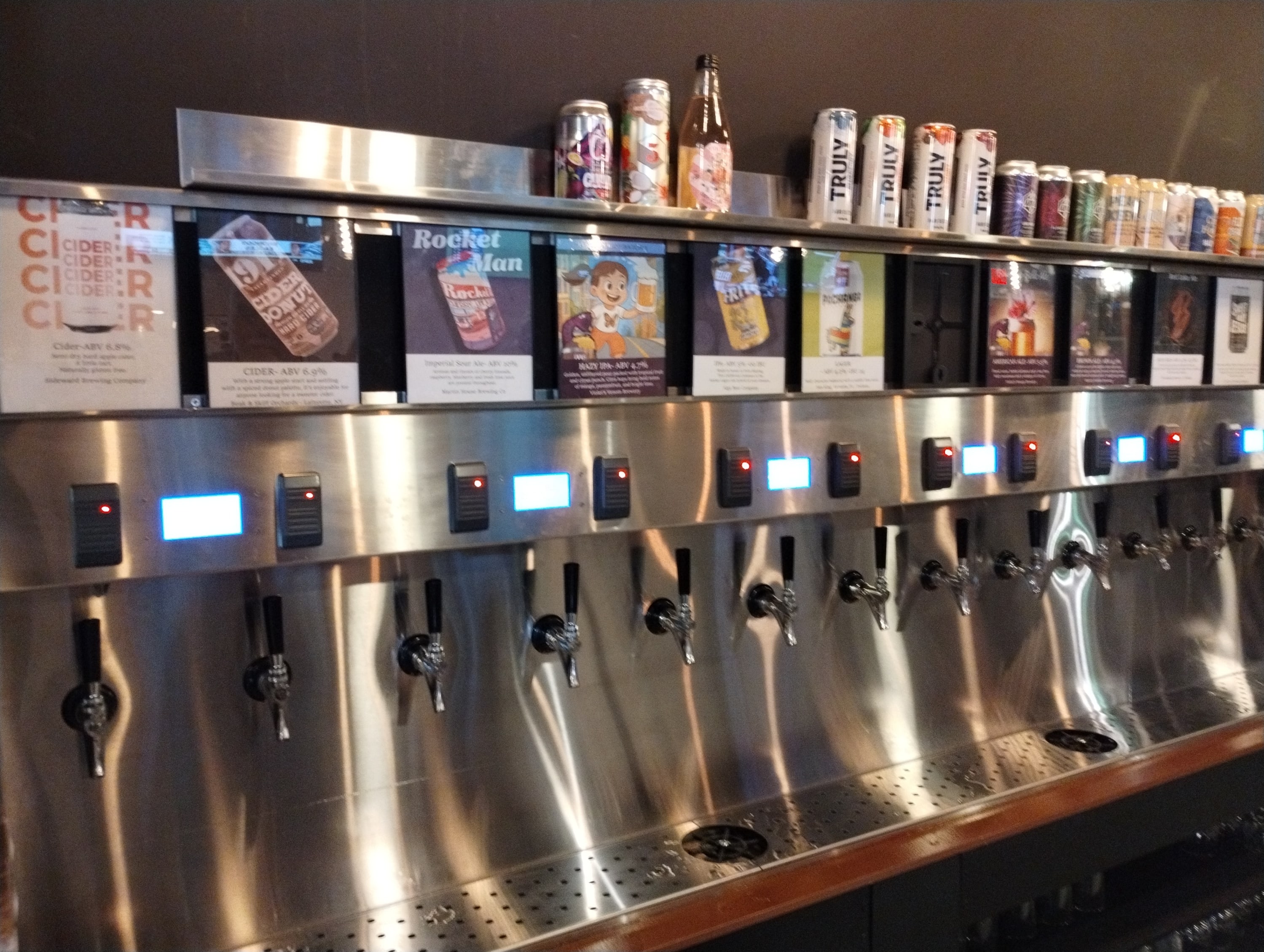 A self-pour tapwall with descriptions of the beer over the sensor and a display of beer on top