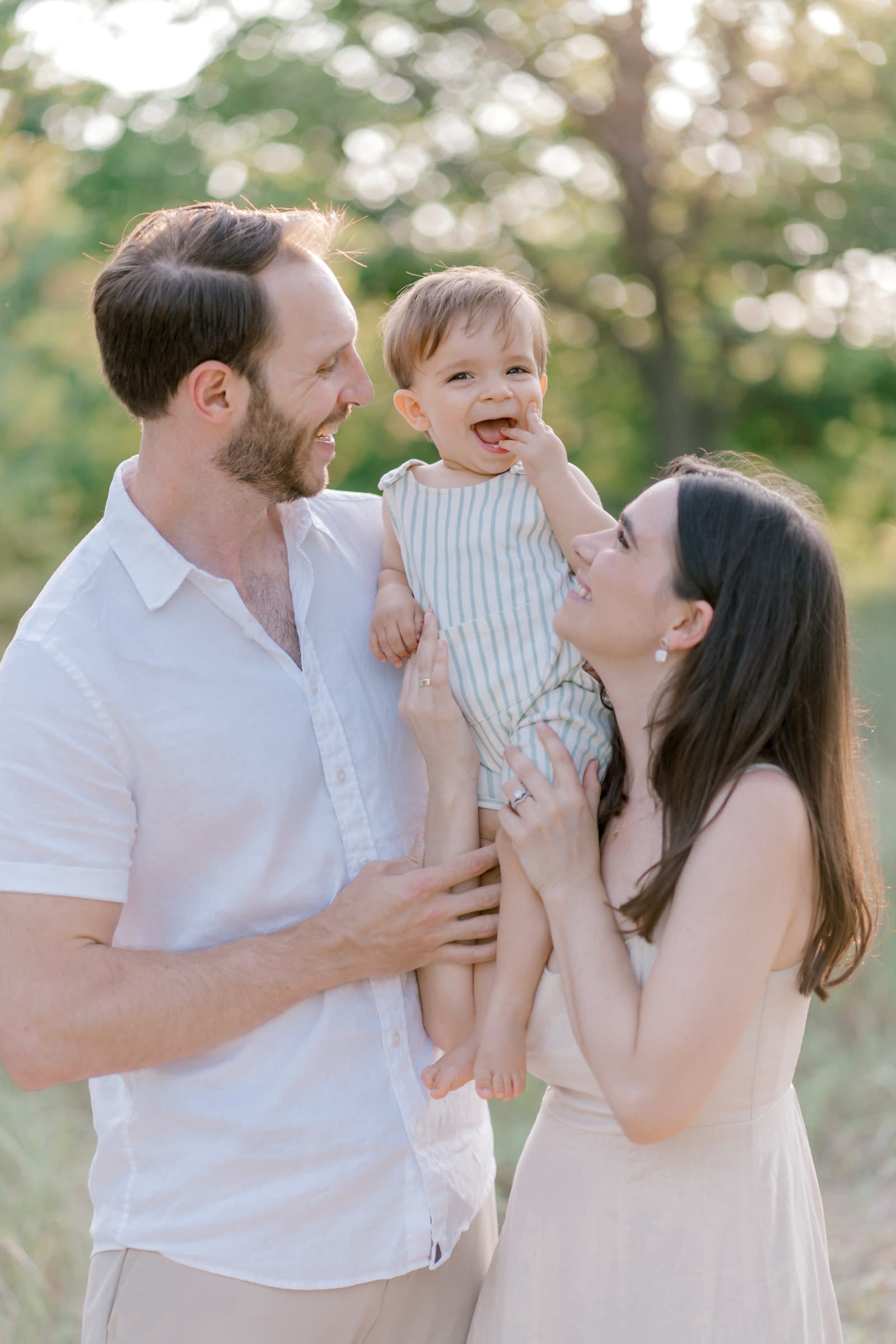 Parents laughing with their toddler son outdoors