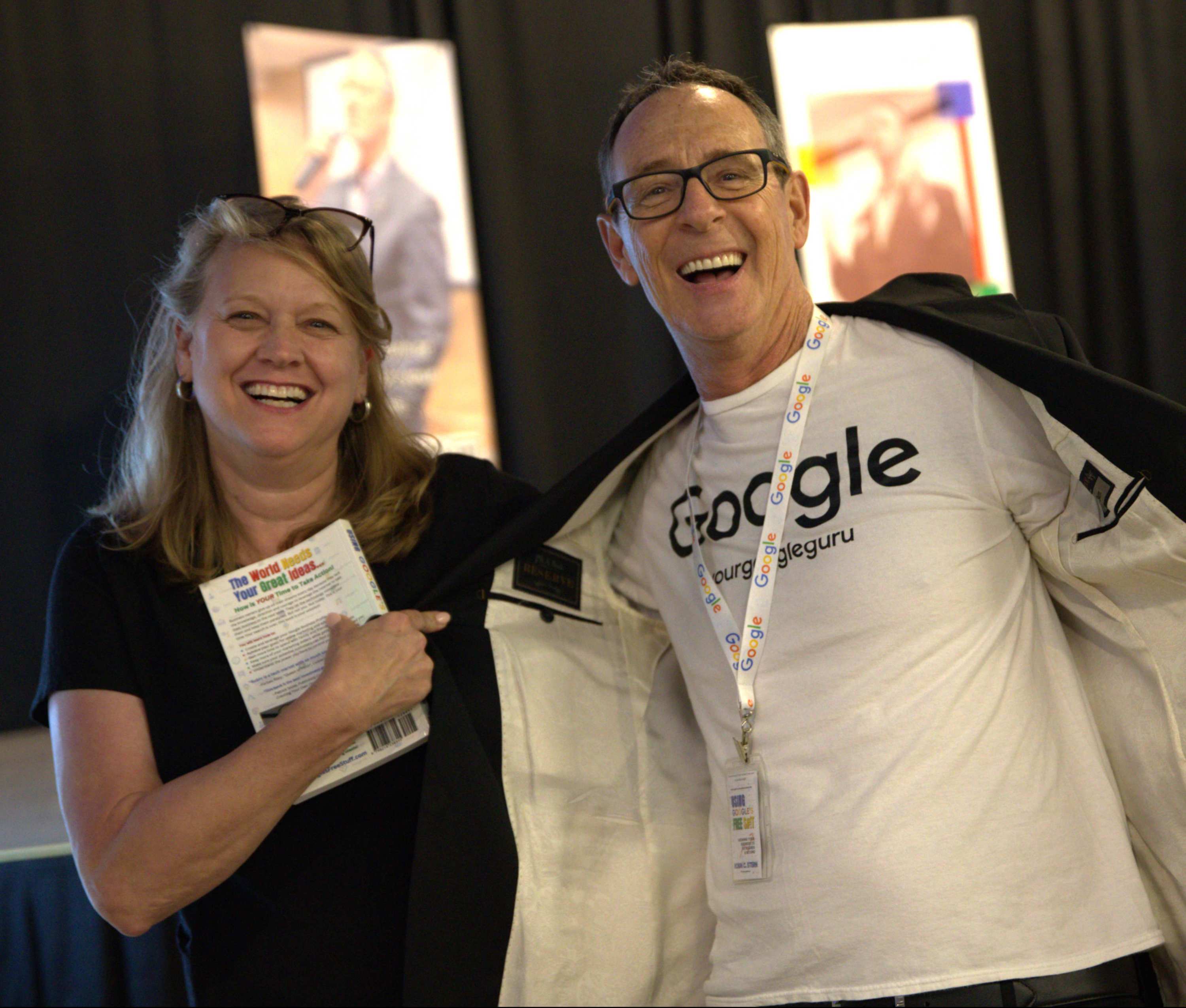 Two smiling people showing off the man's tee shirt saying Google #RobinCStern #YourGoogleGuru