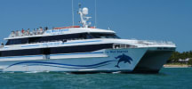 White and blue Key West Express catamaran ferry cruises through ocean waters with passengers on deck