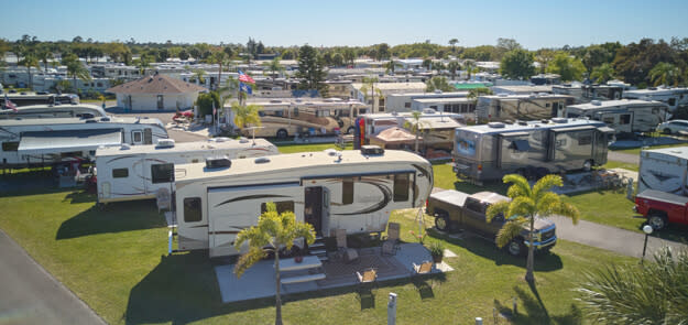 Aerial view of RV park with numerous motorhomes and travel trailers on grassy pads