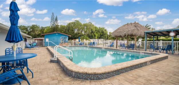 Swimming pool with thatched tiki hut and blue patio furniture