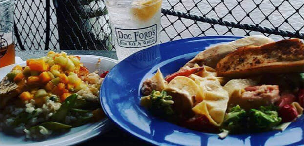 Two plates at Doc Ford's: mixed vegetables with rice beside pasta with chicken and garlic bread