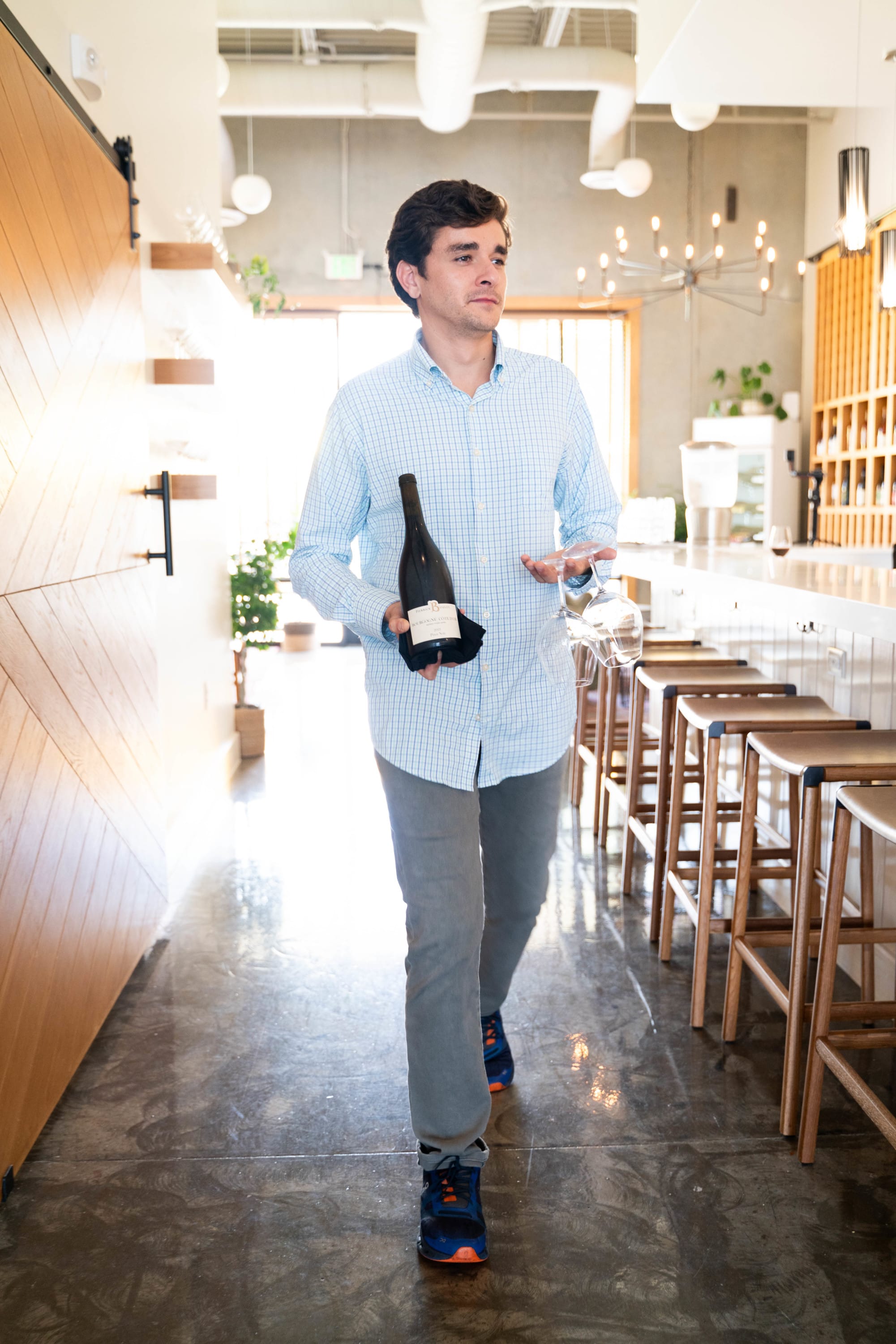 General Manager of Sonoma Wine & Cheese in Katy, TX carrying a wine bottle inside the wine bar