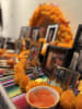 A Dia de los Muertos Altar with marigolds, oranges, butterflies, and framed pictures of family.