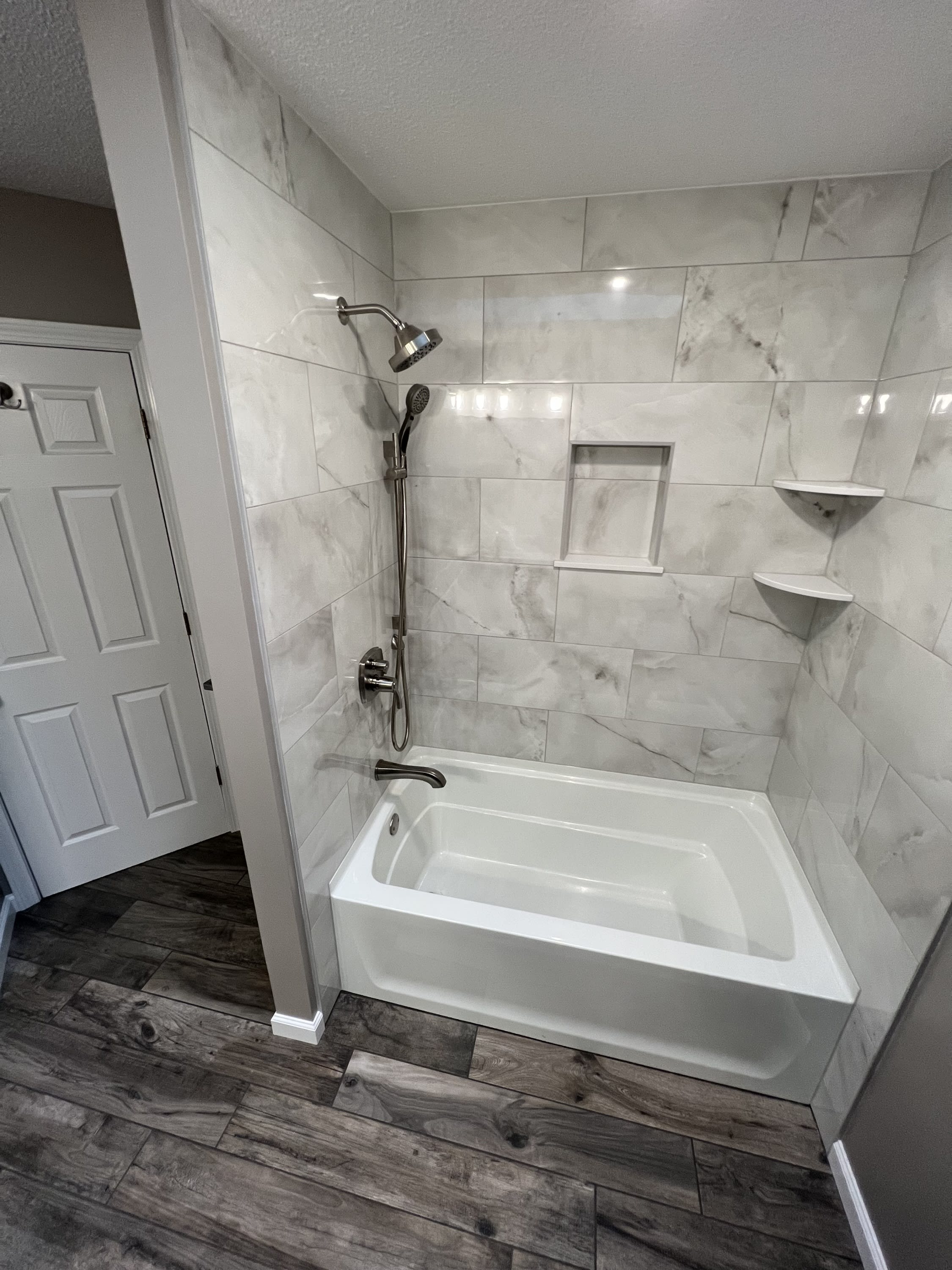 Completed bathroom remodel with marble-look tile tub and shower by Sosnin Builders