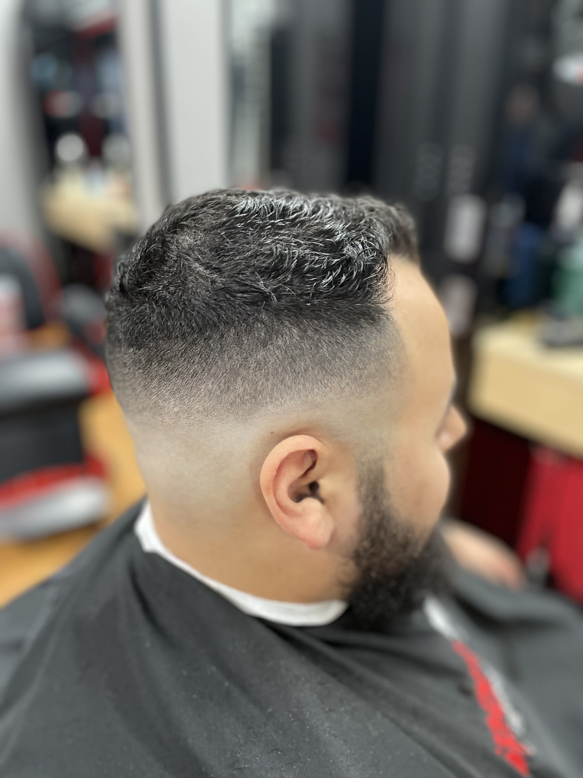 Skin fade haircut by barber Danny, blended into a natural textured top, at Sport Clips Haircuts. Serving Sarasota and Manatee