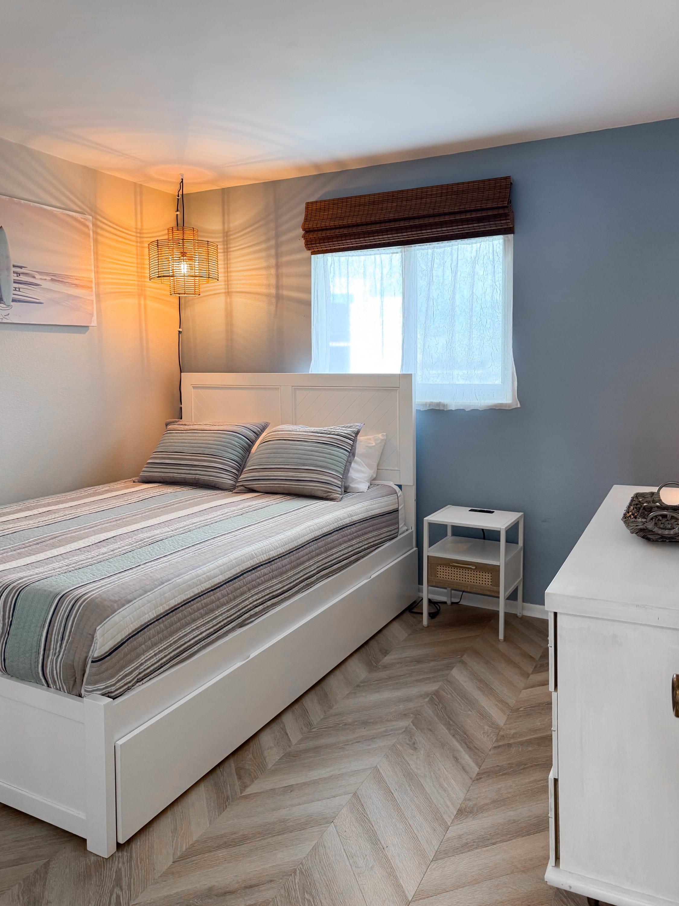 Second bedroom with a queen bed, striped bedding, and a twin XL trundle underneath, at Coastal Dreams.