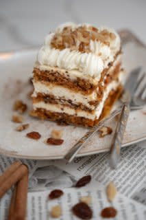 Layered gluten-free cake slice with cream filling, nuts, and elegant presentation