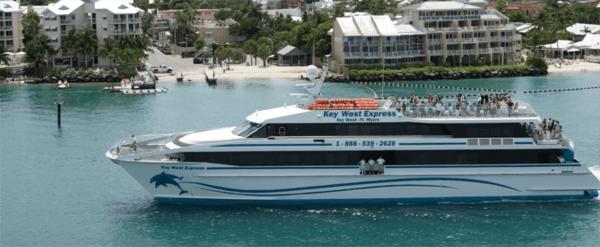 Key West Express tour ferry with passengers cruising through turquoise harbor waters with coastal buildings
