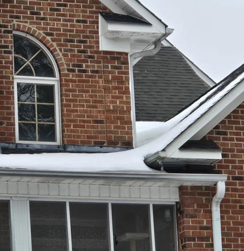Roof with snow and ice accumulation on shingles and gutters