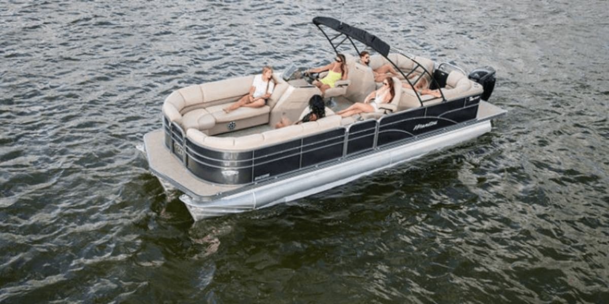 Pontoon boat cruising on water with passengers relaxing on beige seating under black canopy.