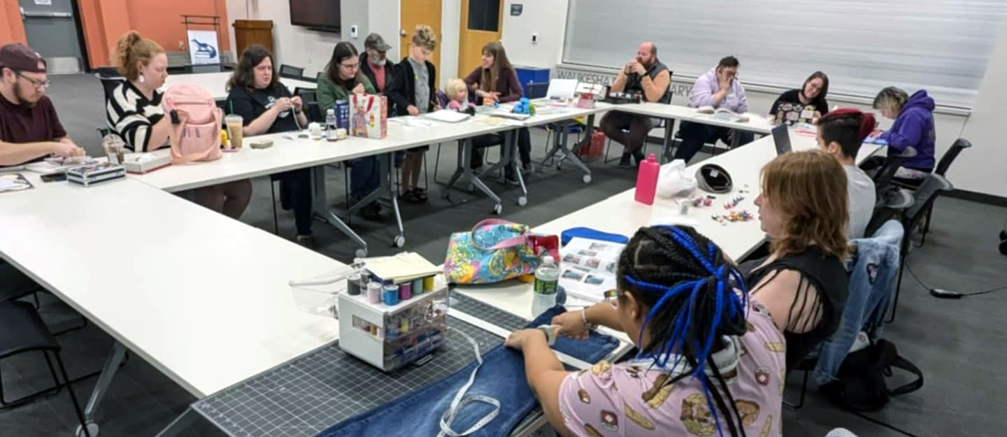 14 people around a table working on a variety of crafts.