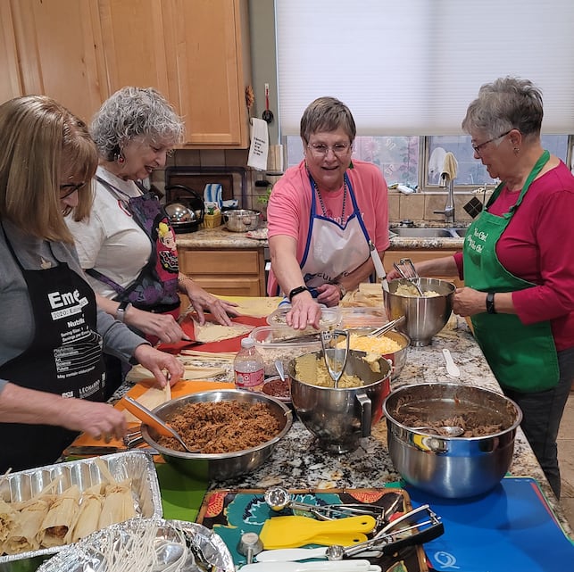 Women gathered in a kitchen making tamales