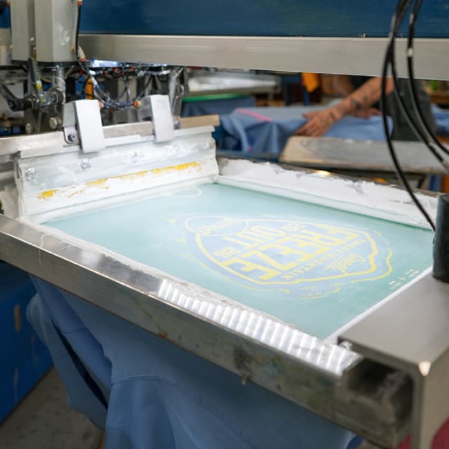 screen printing production run showing a screen with a custom design using white ink