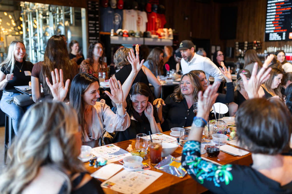 group of women laughing with their hands in the air.