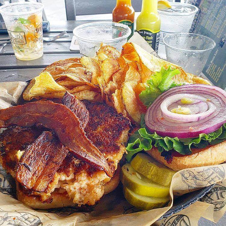Crispy fried fish sandwich with bacon plus separate burger with lettuce, onion, pickles, and potato chips