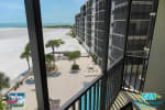 Balcony view of sandy beach, pool, and resort buildings with ocean horizon
