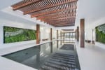 Indoor reflecting pool with wooden slat ceiling beams and green living wall art panels on sides.