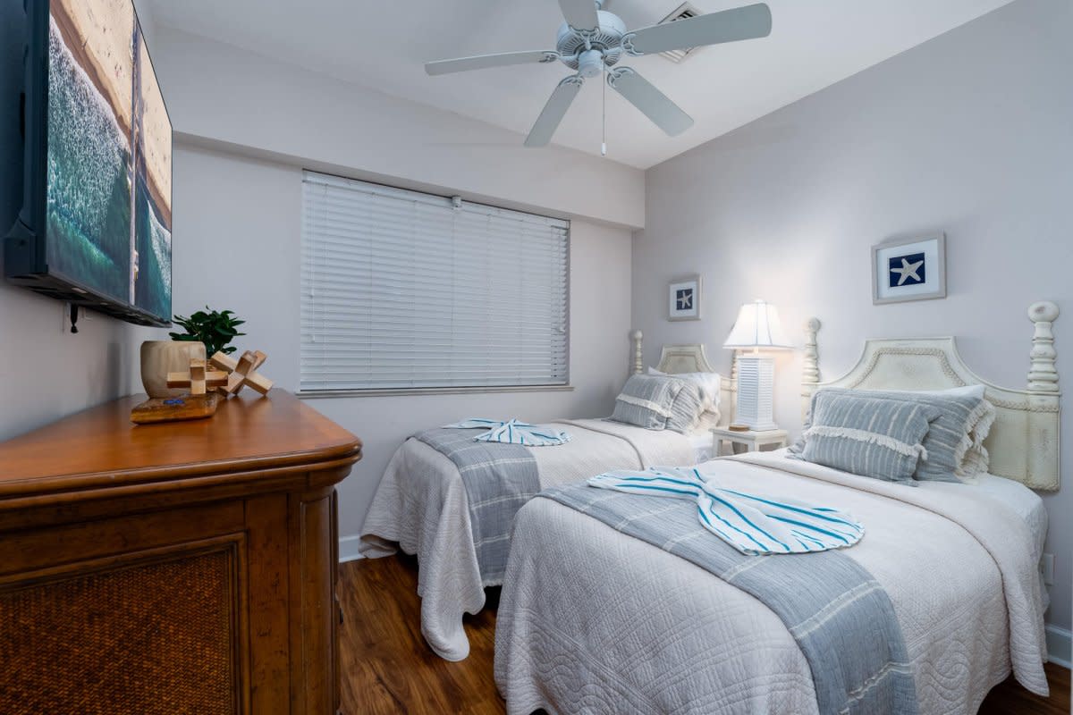 Nautical-themed room with two twin beds, gray walls, wooden dresser, and maritime decor