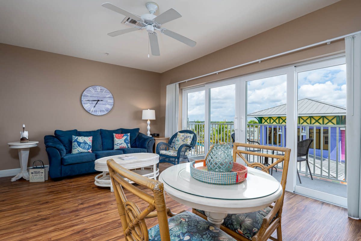 Coastal living area with blue sofa, rattan dining chairs, sliding doors to balcony view
