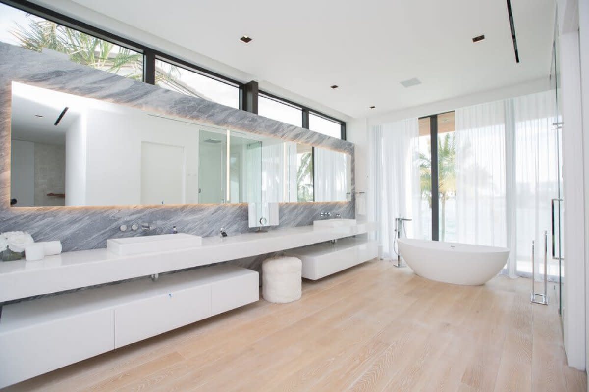 Luxury bathroom with dual sinks, marble backsplash, freestanding tub, and floor-to-ceiling windows.