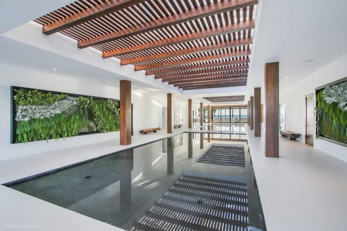 Indoor reflecting pool with wooden slat ceiling beams and green living wall art panels on sides.