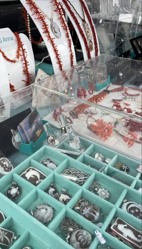 Display case with coral necklaces and assorted silver jewelry arranged in organized teal compartments.