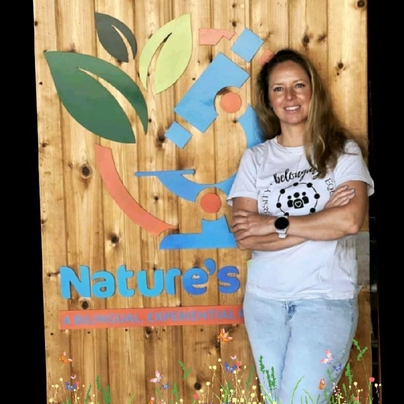 Silvia Anderson standing next to Nature's Lab School Logo
