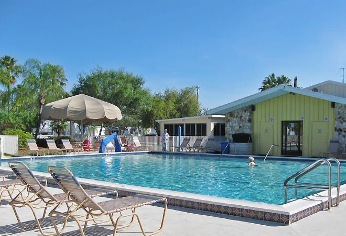 Swimming pool with lounge chairs, umbrellas and clubhouse on clear day