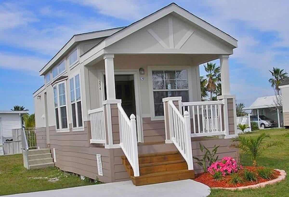 Small vacation home with front porch, white railings and pink flowers