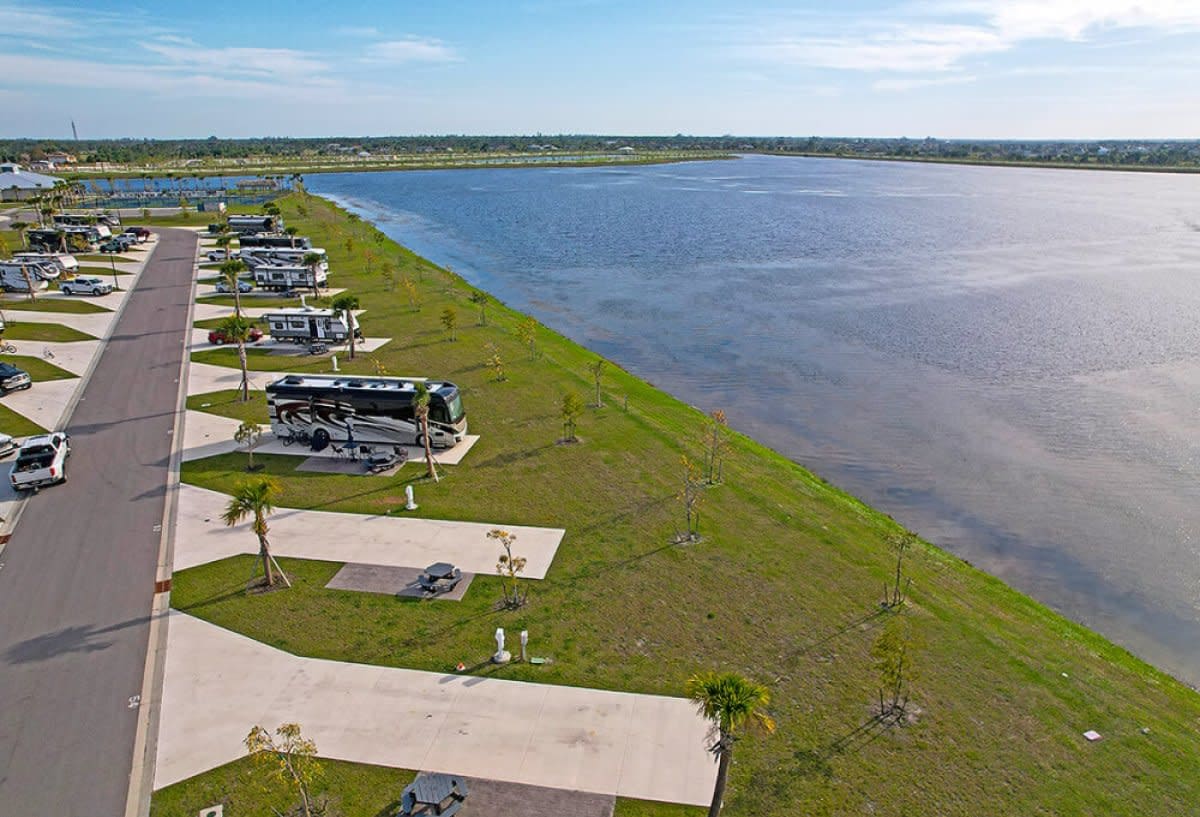 Aerial view of RV sites lined along grassy lakeshore with concrete pads