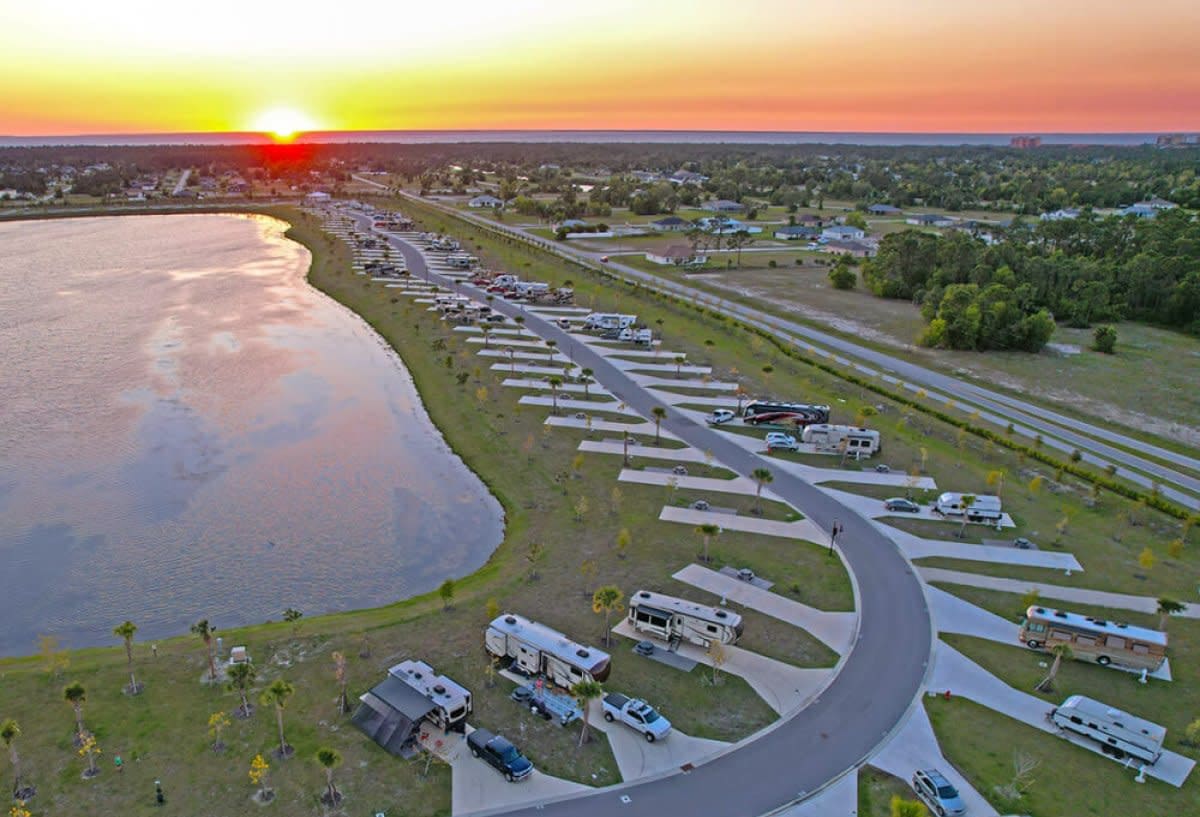 Sunset aerial shot of RV park curving along waterfront at golden hour