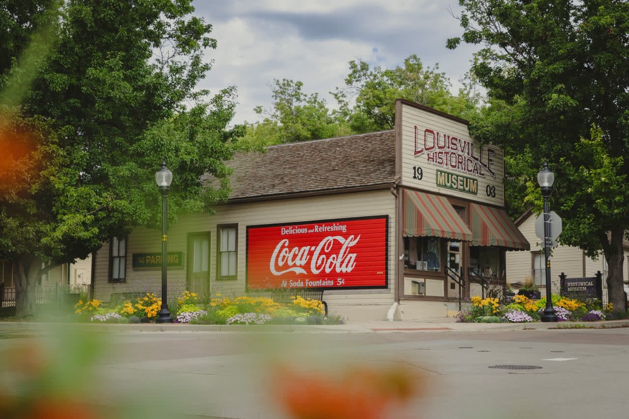 Louisville Historical Museum main building. It is a wooden building with a false front and Coca-Cola mural painted on it.