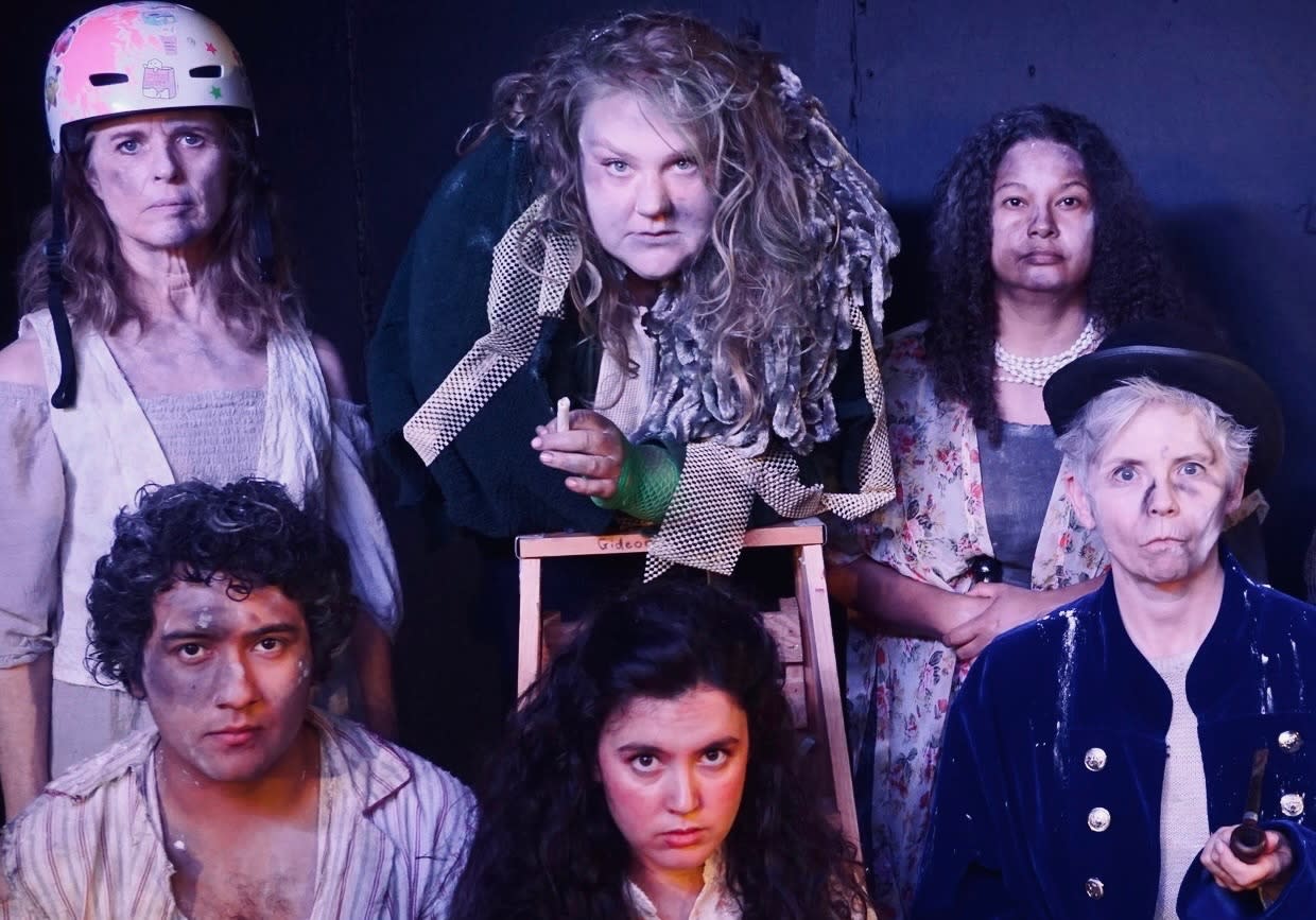 6 people in unique, disgruntled costumes in a formation looking very serious.