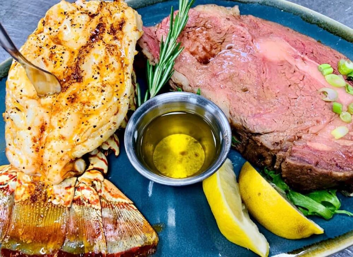 Surf and turf plate with grilled lobster tail, roasted beef, lemon wedges, and olive oil dip