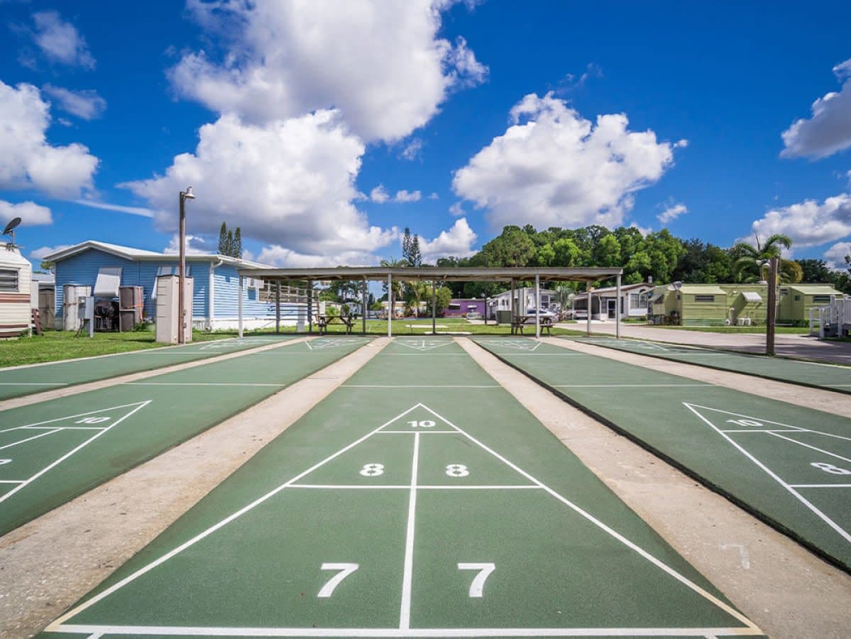 Multiple shuffleboard courts with scoring zones and mobile homes nearby