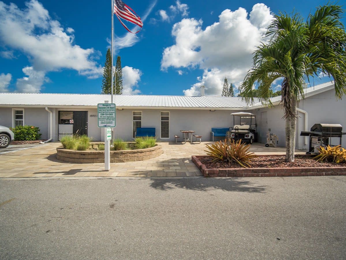Clubhouse building exterior with flagpole, palm tree and golf cart