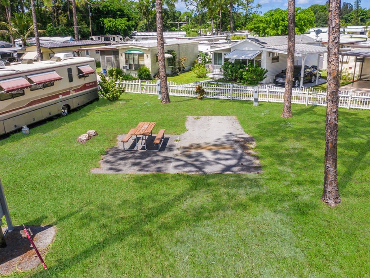 RV park yard with picnic table, white picket fence and palm trees