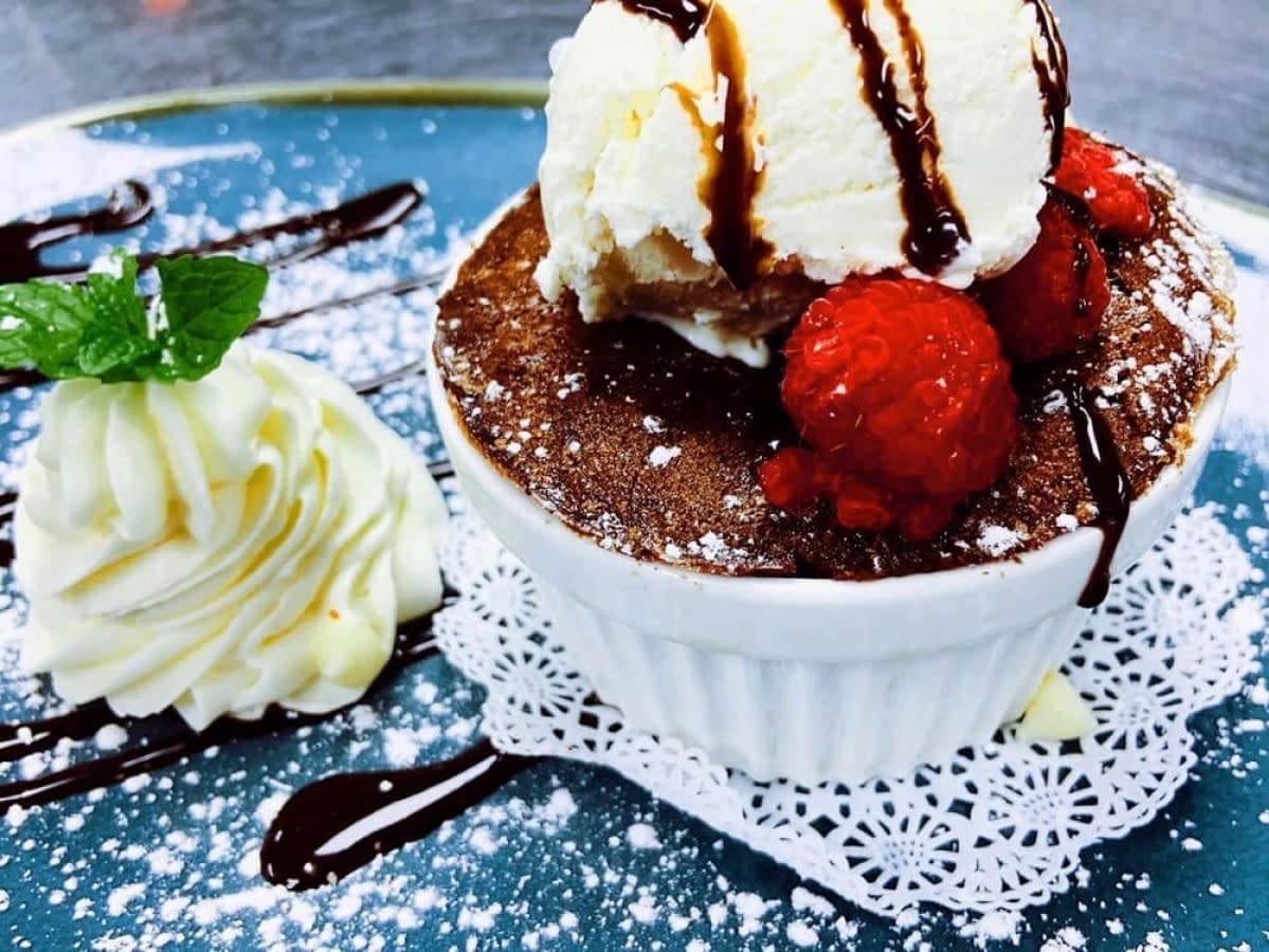 Chocolate lava cake dessert with vanilla ice cream, raspberries, powdered sugar, and mint garnish
