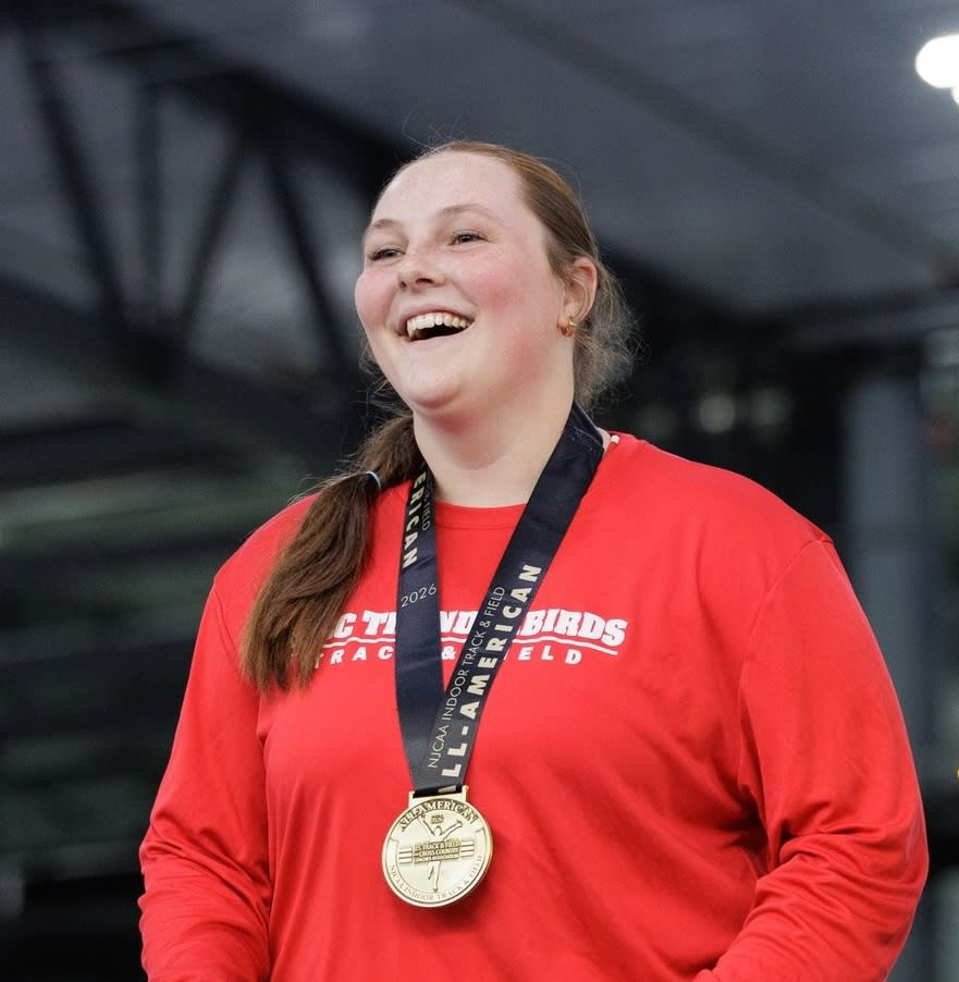 Woman wearing a red top and a gold medal award