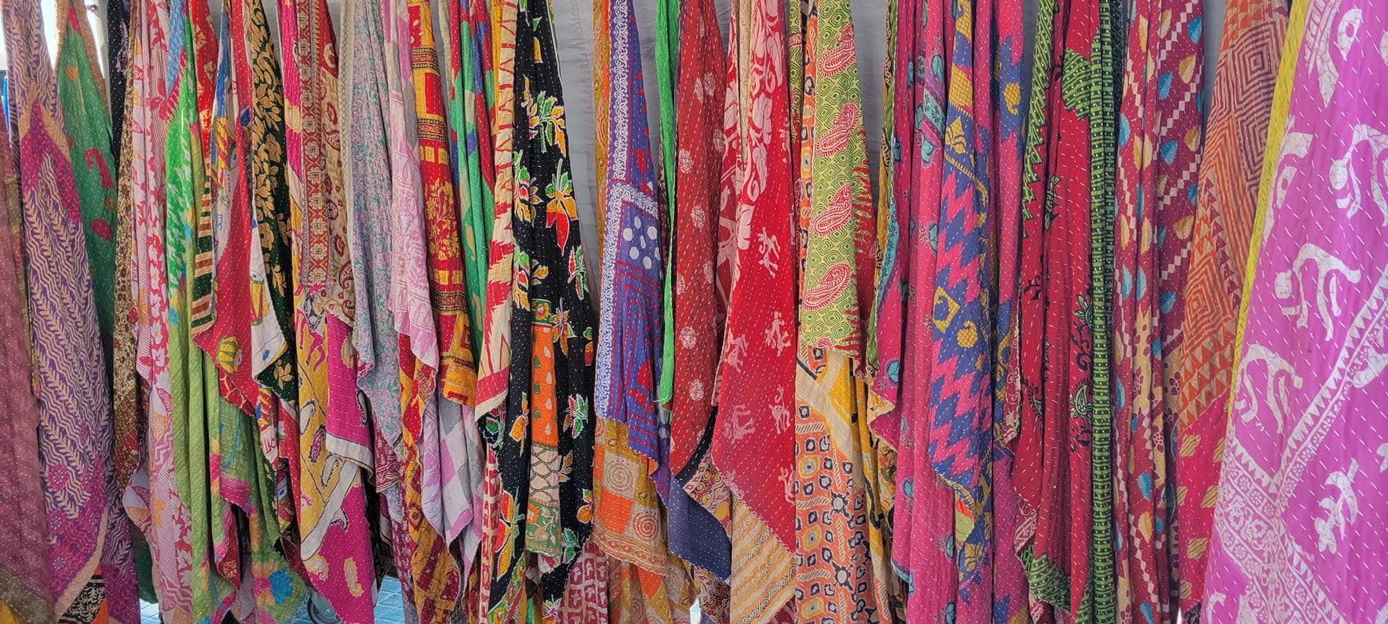 Vibrant collection of colorful patterned scarves and fabrics hanging for sale at a market stall