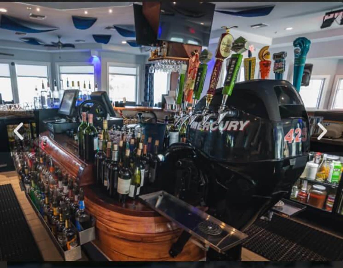 Bar interior featuring Mercury outboard motor decor, beer taps, and extensive liquor bottle display
