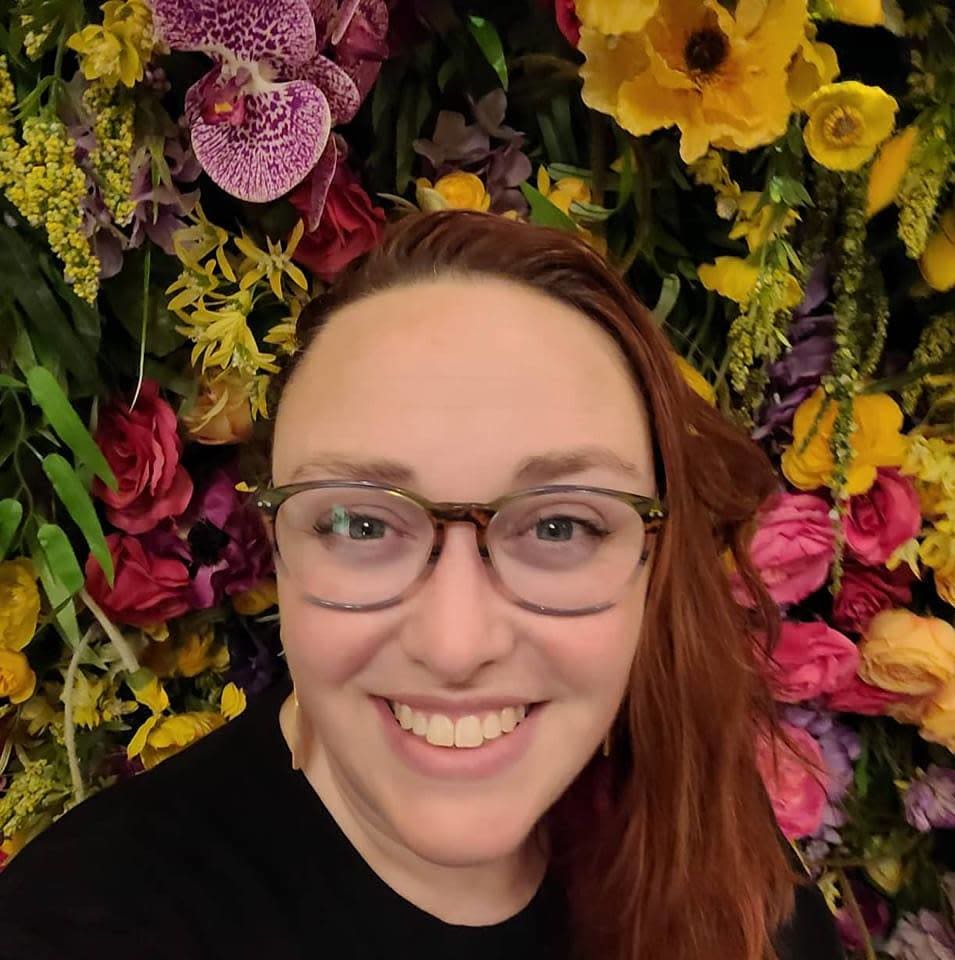 close up selfie of Dania in from of a floral wall.
