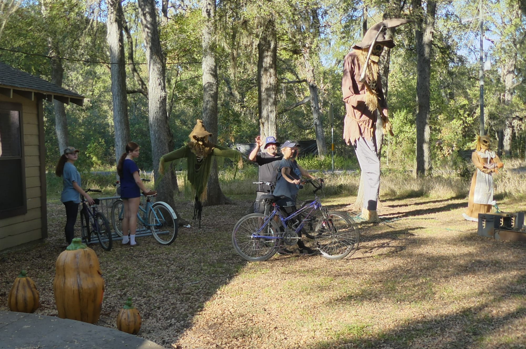 family with bicycles in front of a building with scarecrow decorations