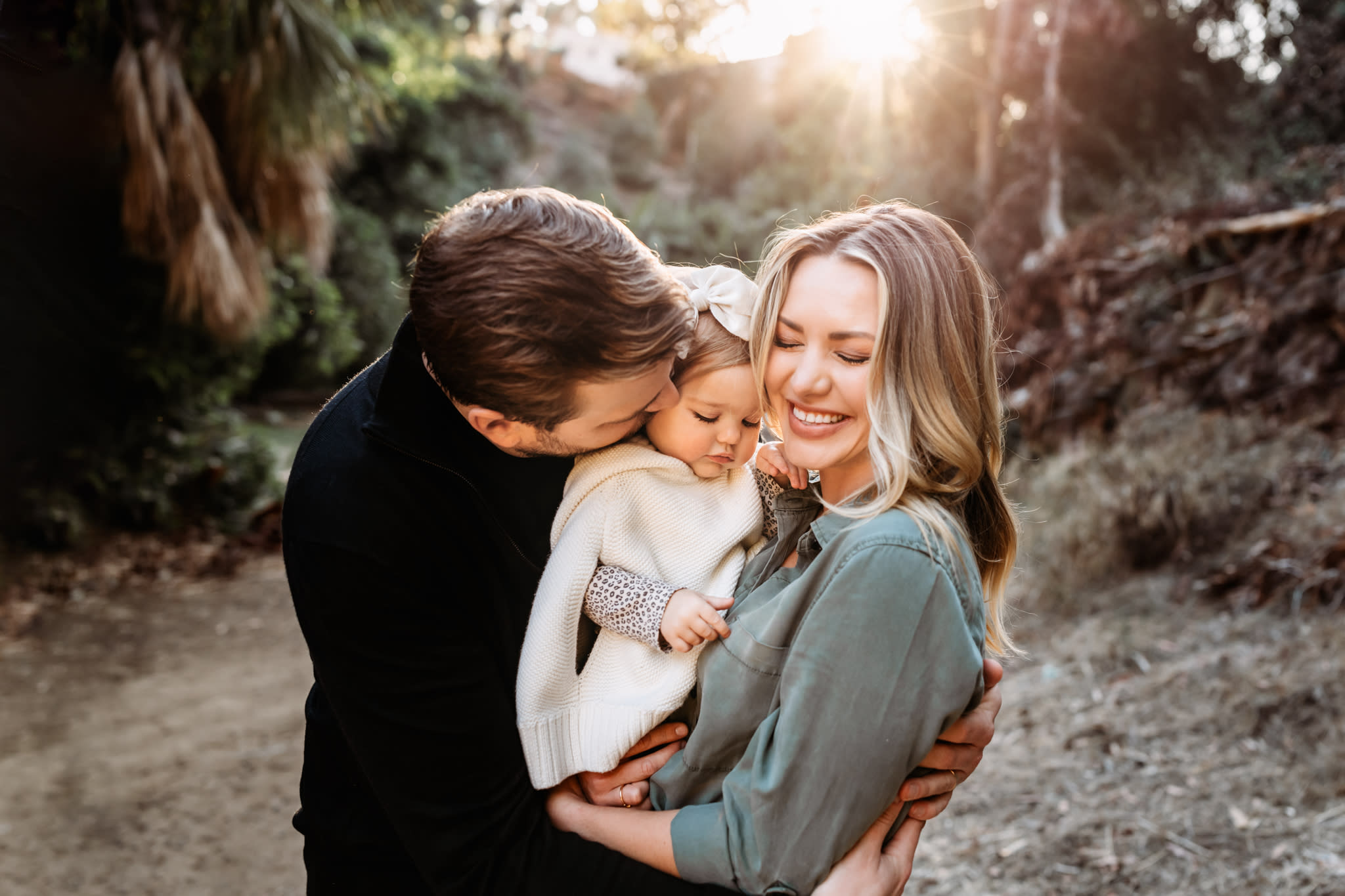 Mother, father, and toddler daughter snuggle in for family hug