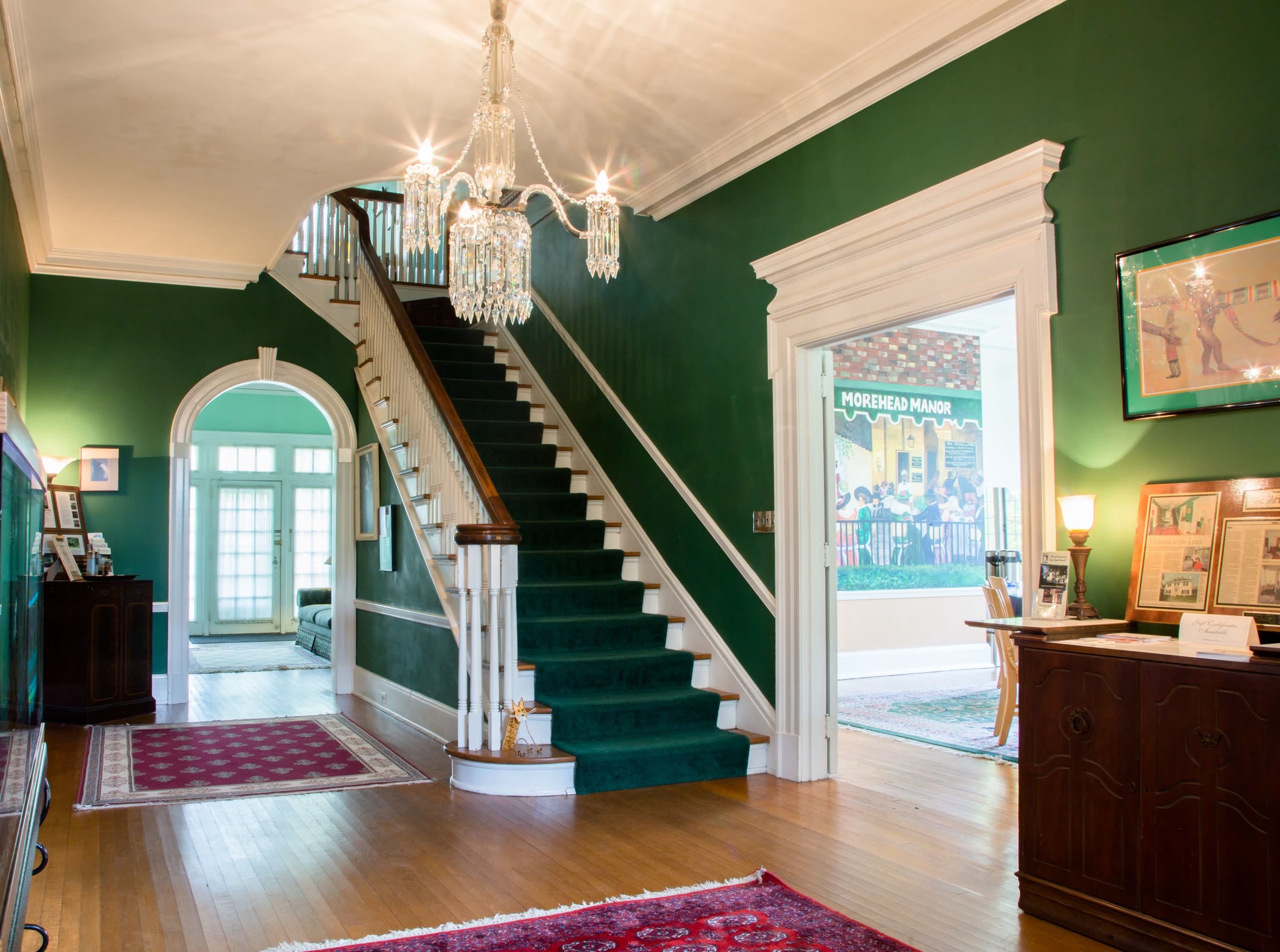 Foyer with green carpeted steps to the 2nd floor with Mural in the distance